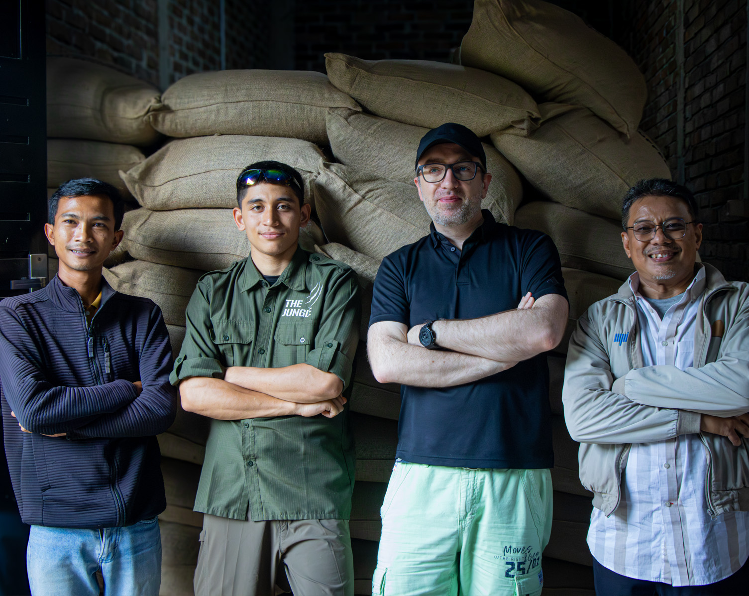The Jungle Coffee team standing in front of green coffee bags at the warehouse